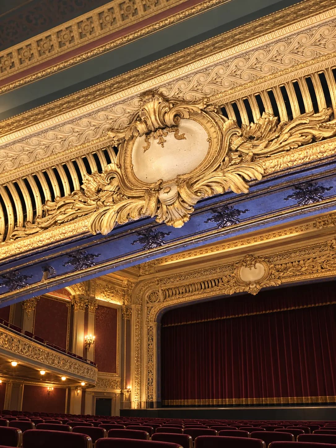 Interior of a restored historic picture palace with ornamental plasterwork, a curved balcony front and warm lighting picking out the mouldings