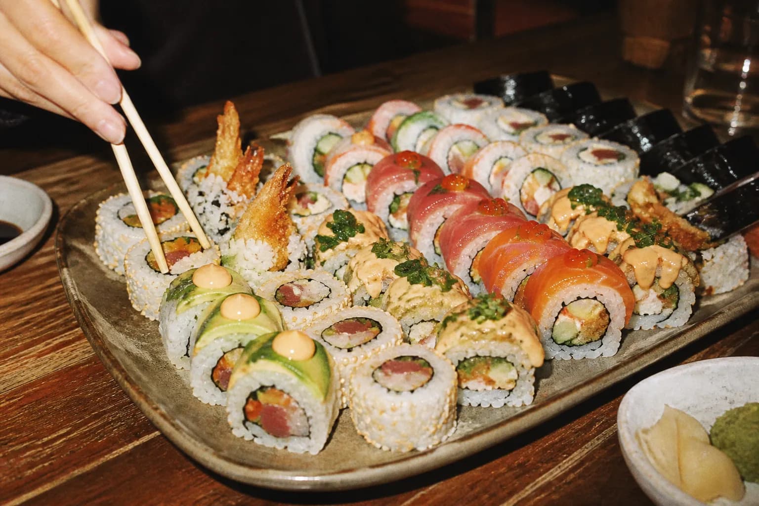 A generous platter of assorted sushi rolls arranged for sharing at a restaurant table
