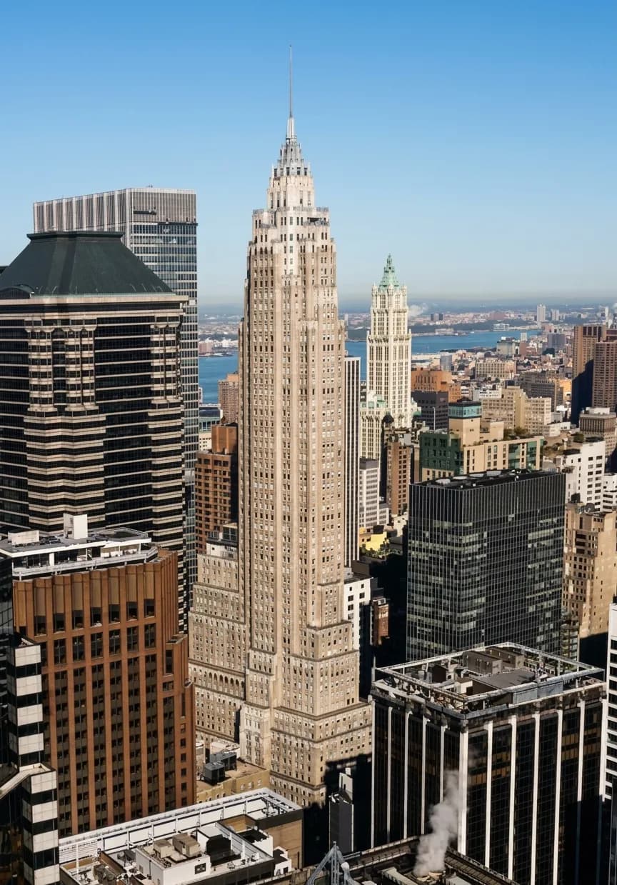 Art Deco limestone tower of 70 Pine Street rising above the Financial District skyline on a clear day