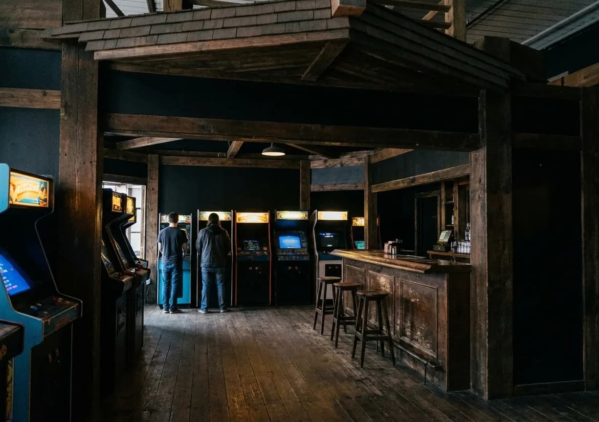 Vintage arcade cabinets glowing along the wall of a dark bar