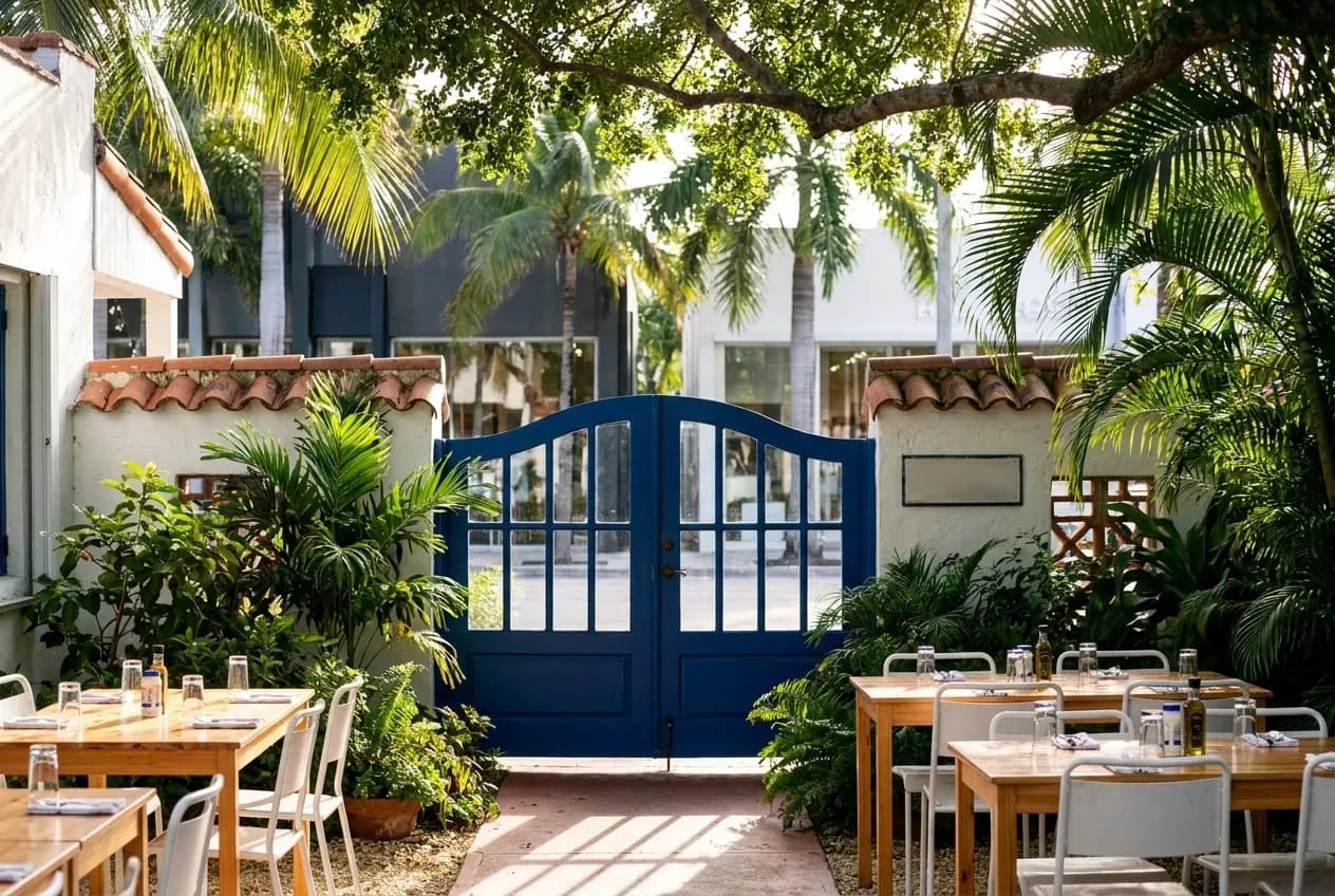 Blue gates mark the entrance to a Mediterranean-style converted bungalow restaurant in Miami's Design District under morning light.