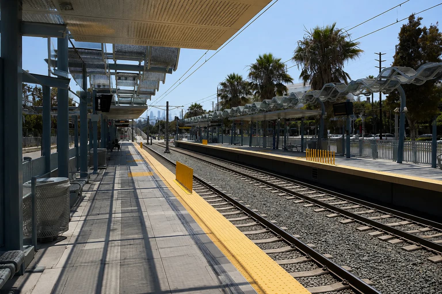 Metro E Line light rail platform in Los Angeles with tracks extending toward downtown