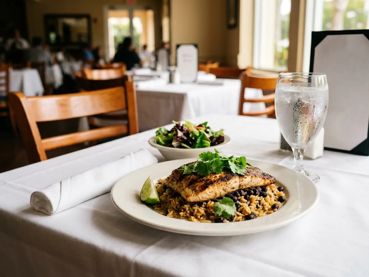 A plated midday course of grilled fish with rice, black beans and lime on a linen-set table in a Miami restaurant