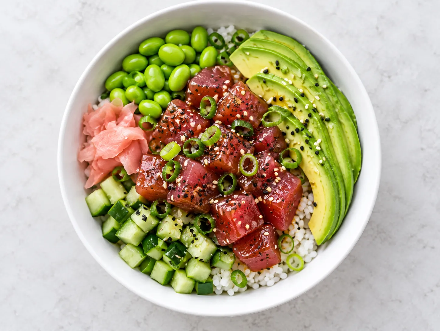 A poke bowl with cubed tuna, rice, avocado and sesame seen from directly above