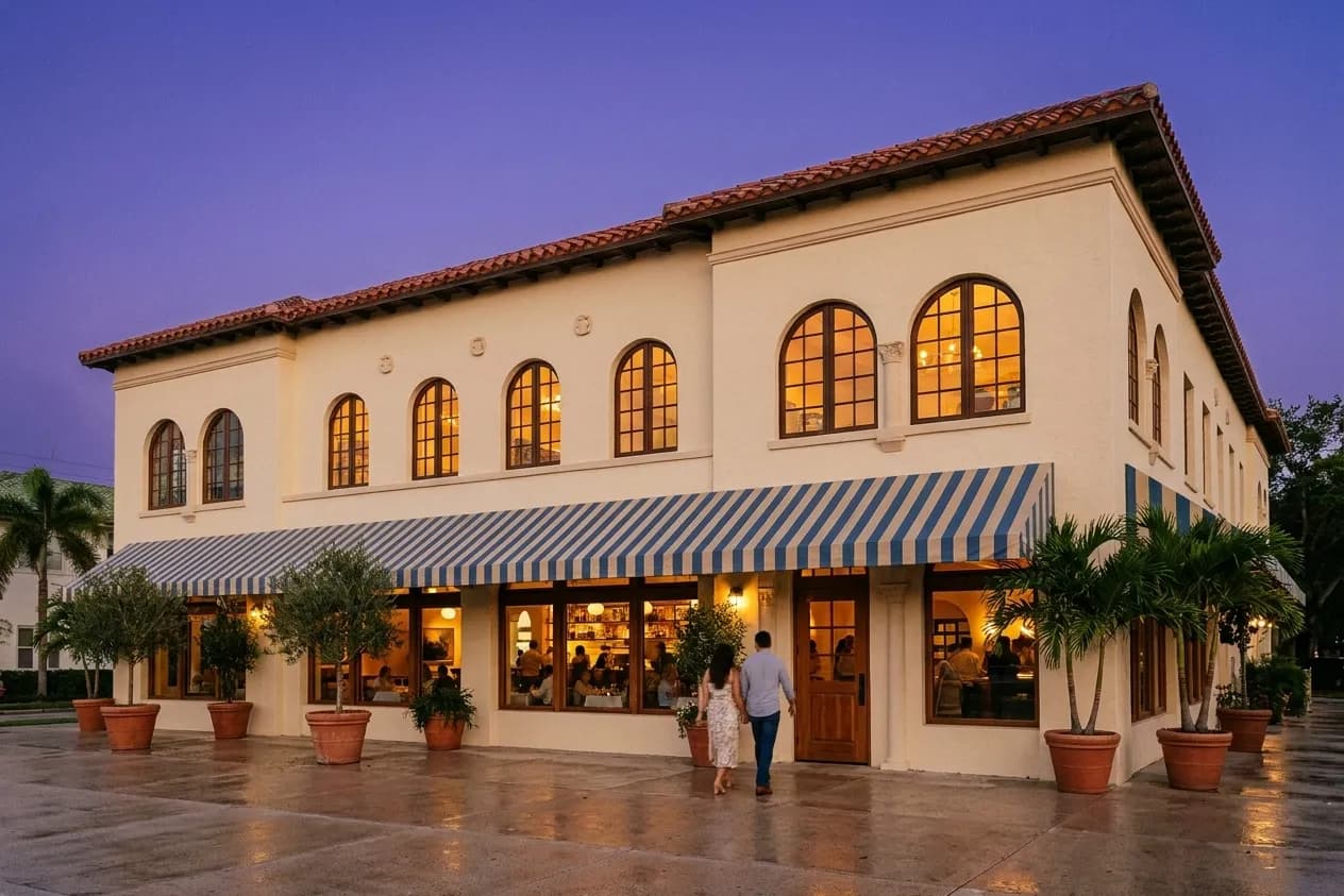 A newly opened restaurant in a Coral Gables Mediterranean-revival building at dusk, arched windows lit from inside