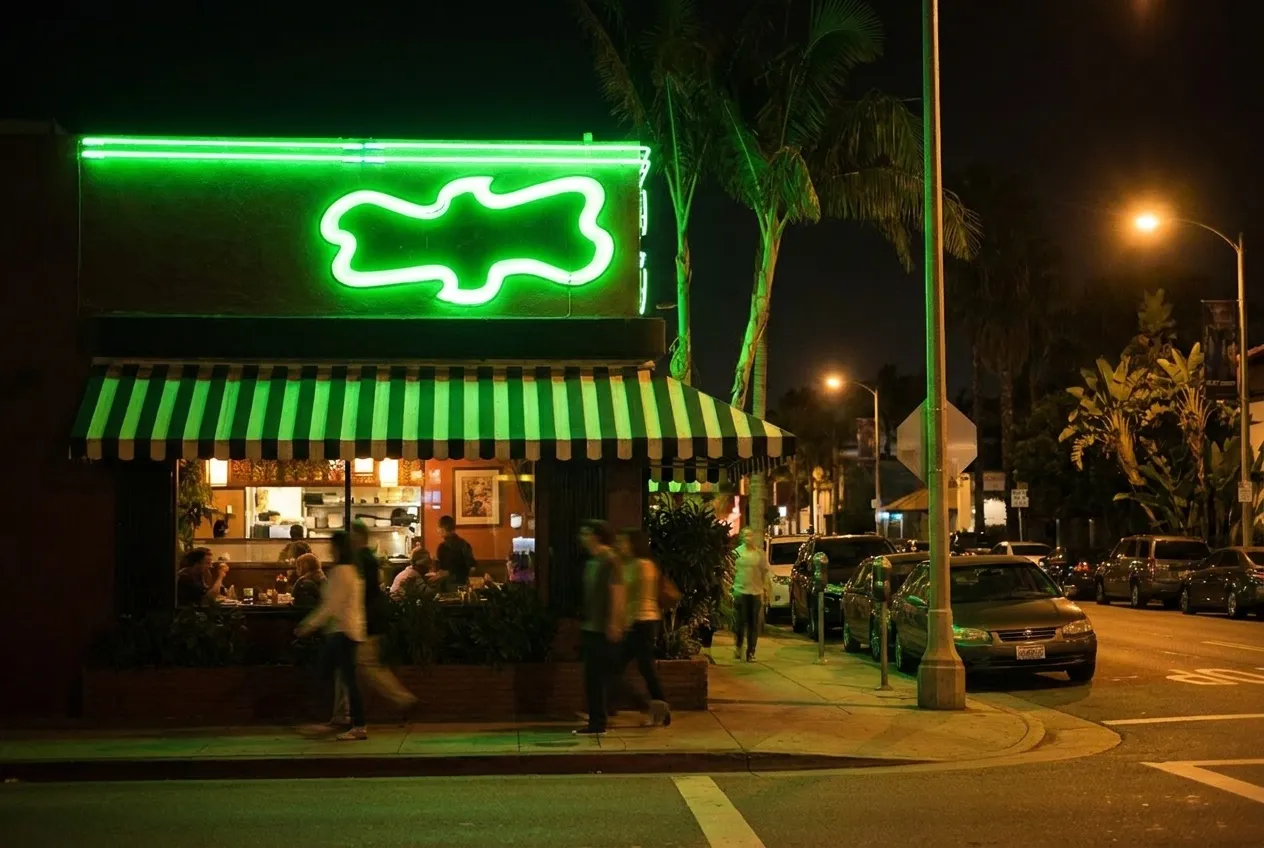 Night street scene outside Los Angeles restaurant with warm interior lighting and pedestrians on sidewalk
