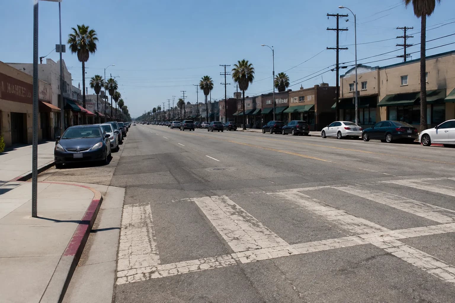 Crenshaw Boulevard in Los Angeles on a sunny summer afternoon, showing commercial storefronts and parked cars along the street
