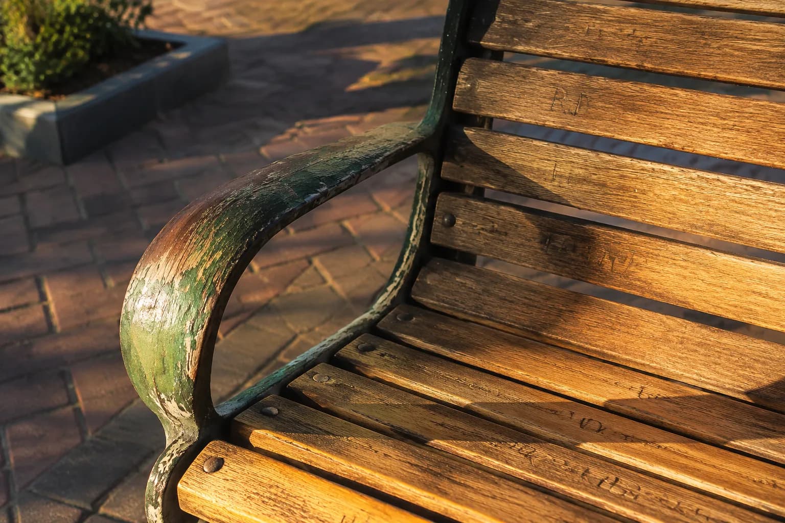 Weathered wooden bench in Leimert Park Village plaza with late afternoon sunlight highlighting the wood grain and paint texture