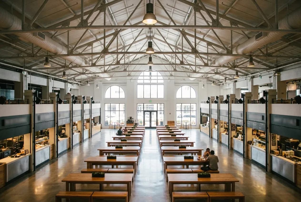 The bright, modern interior of a Miami Beach food hall with communal seating and multiple vendor counters.