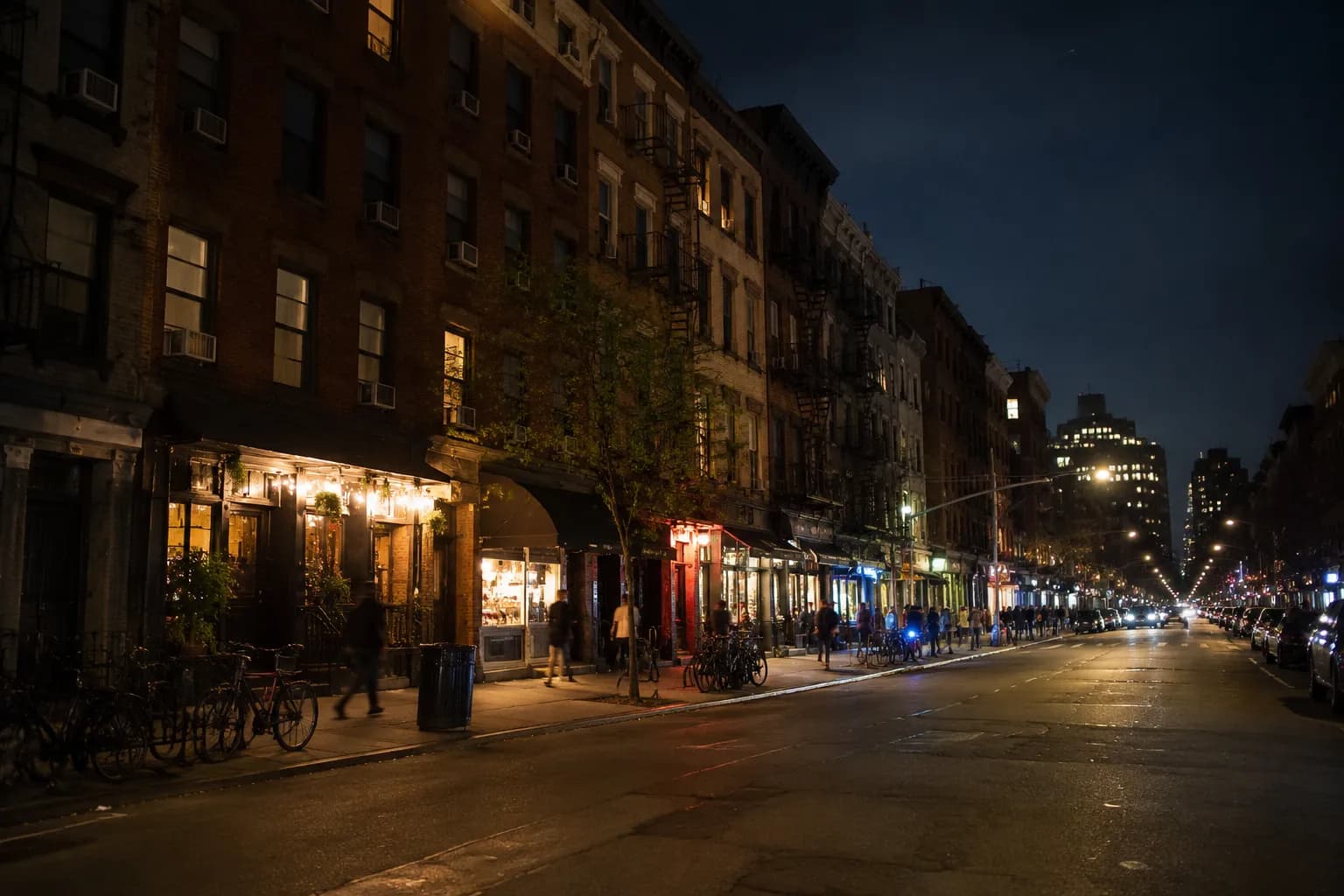 Orchard Street in the Lower East Side at night with illuminated storefronts and pedestrians