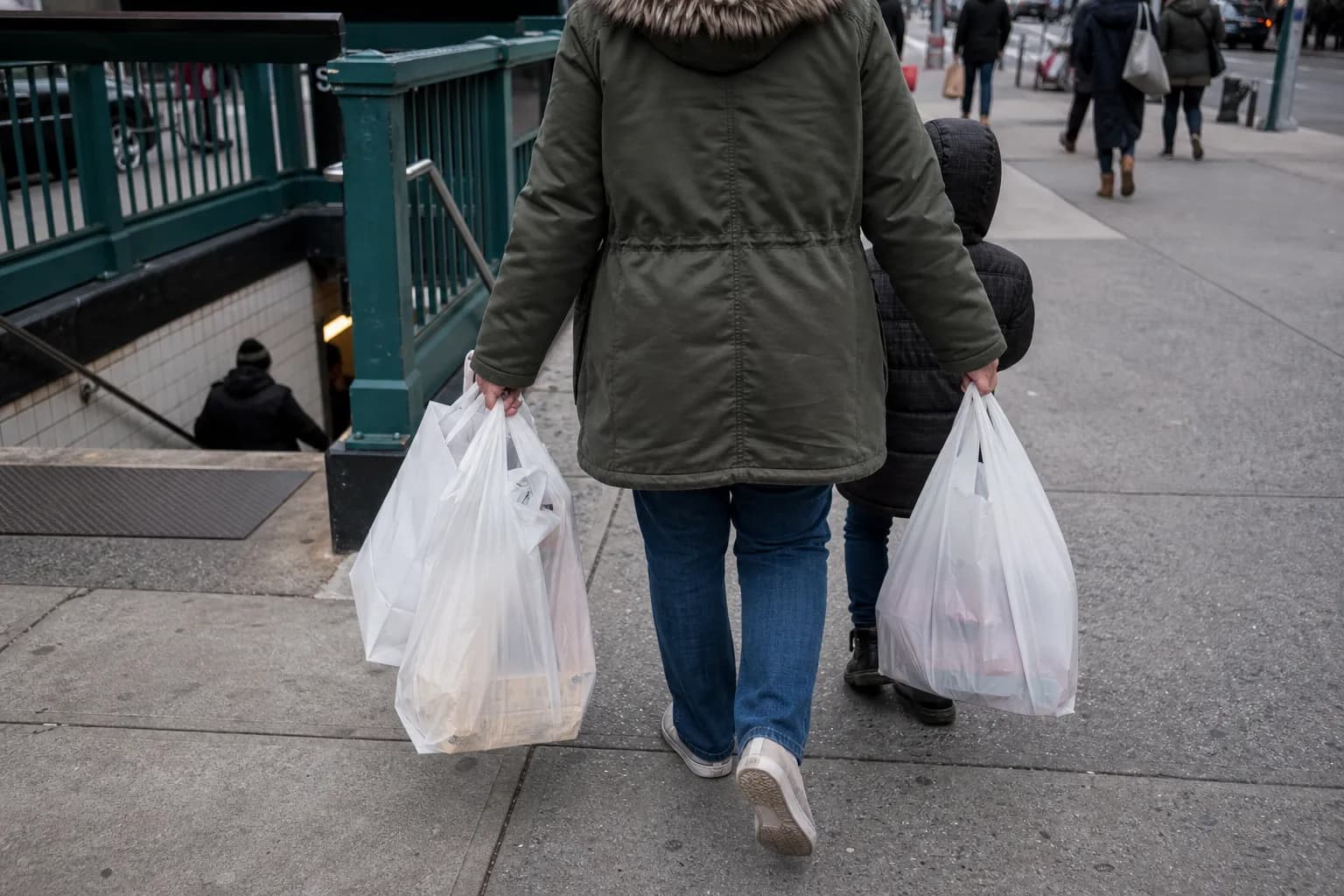 Parents carrying shopping bags near a Manhattan subway stair after shoe shopping