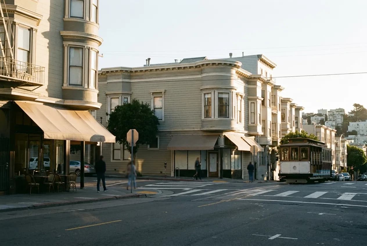 A small San Francisco intersection in morning light with cafe awnings and low buildings