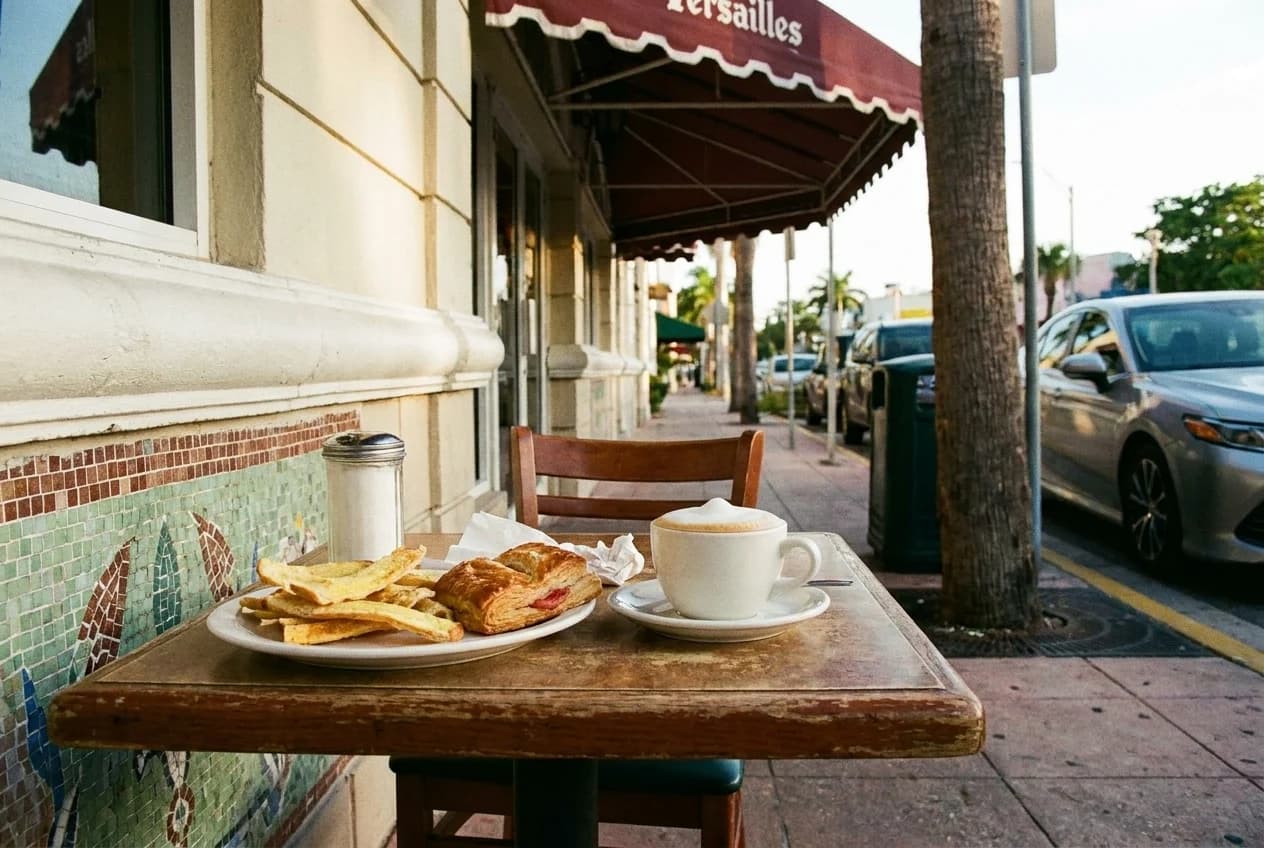 Cafe con leche with espumita foam, tostada strips, and guava pastelito on table