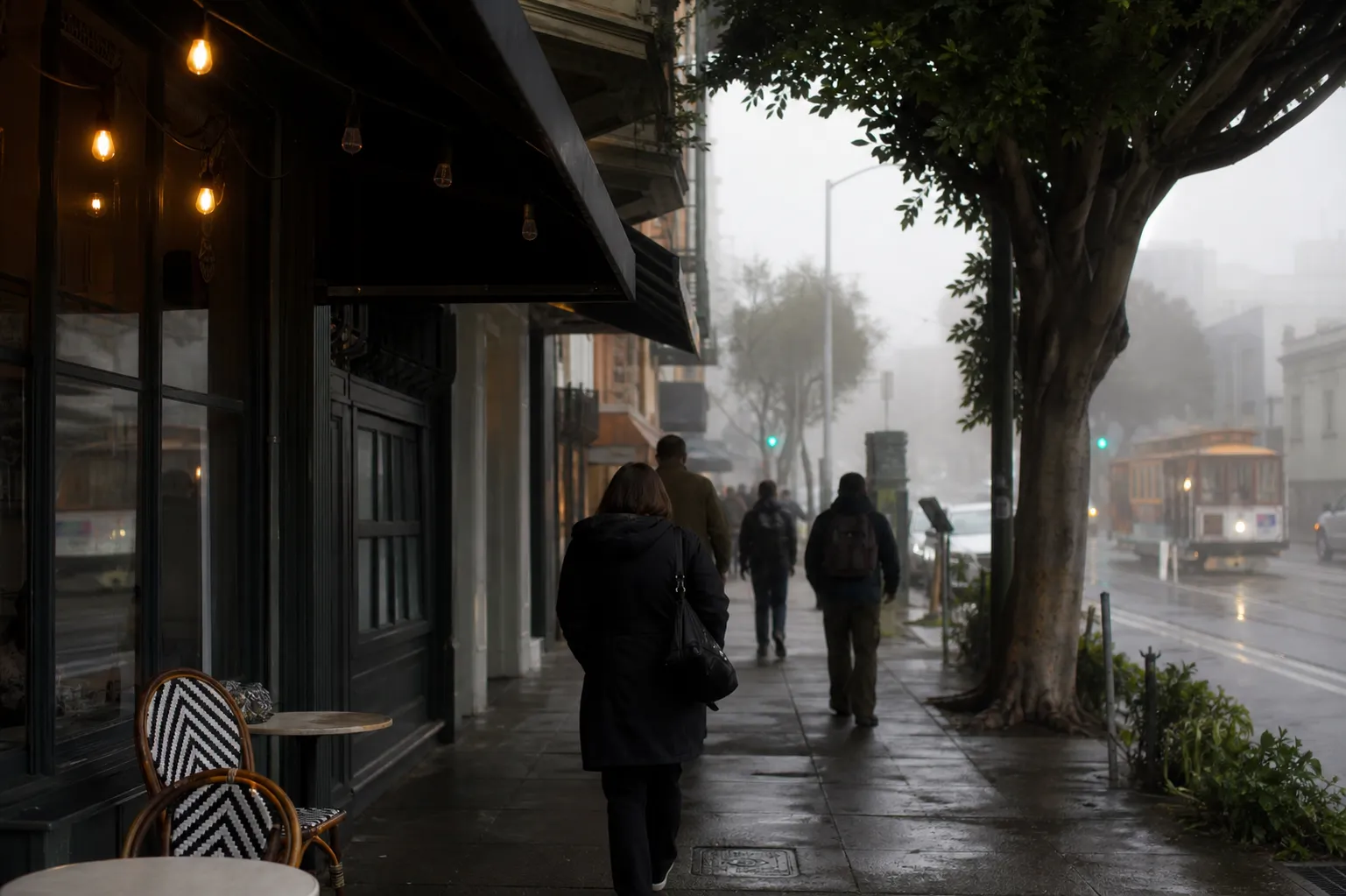 Fog drifting along Columbus Avenue with a café frontage and pedestrians in North Beach.