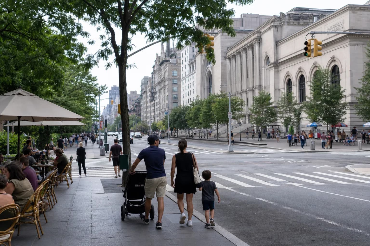 Wide Upper West Side sidewalk with a family walking past cafes near a museum block