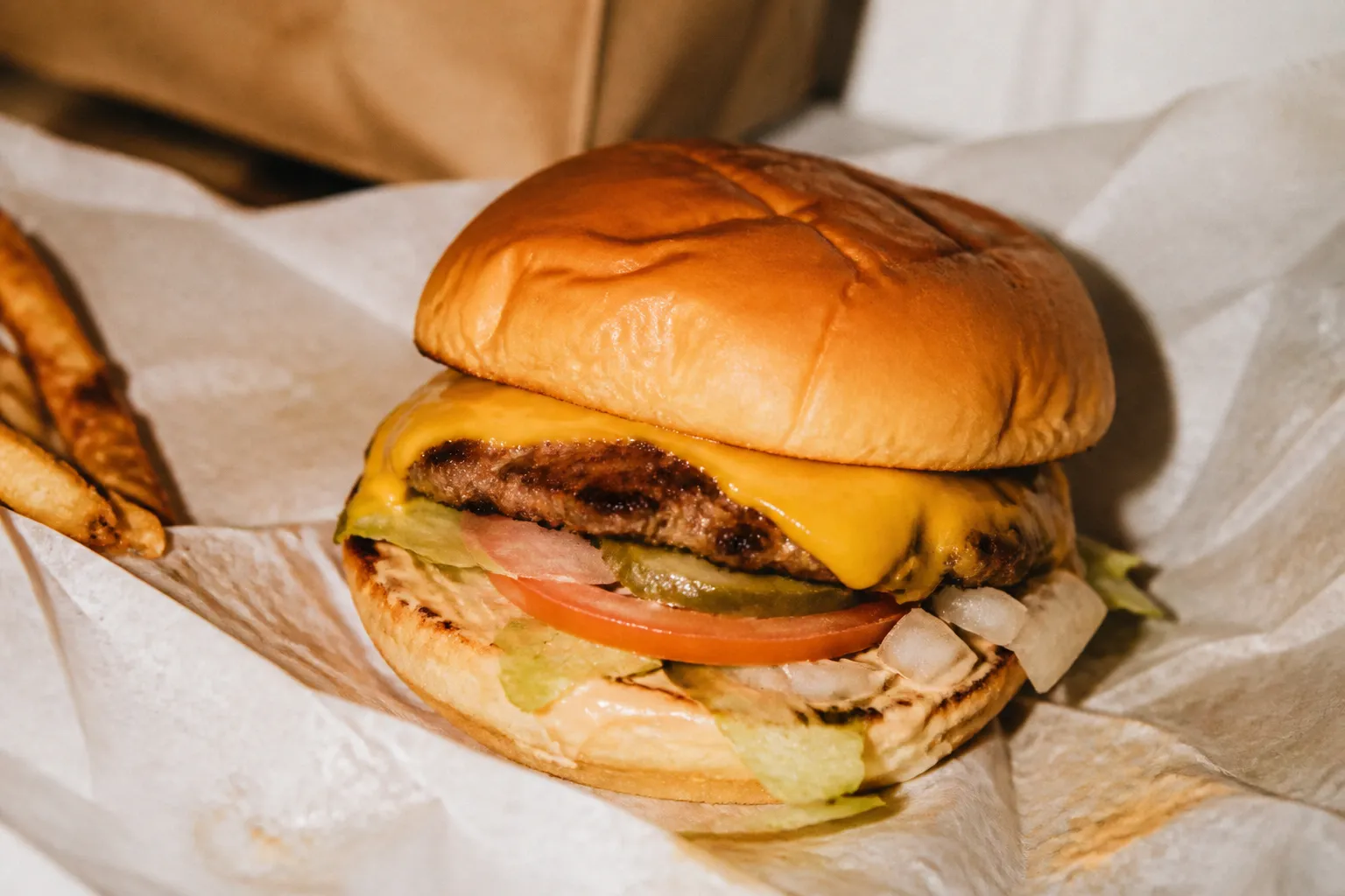 A juicy cheeseburger resting on its wrapper, shown up close