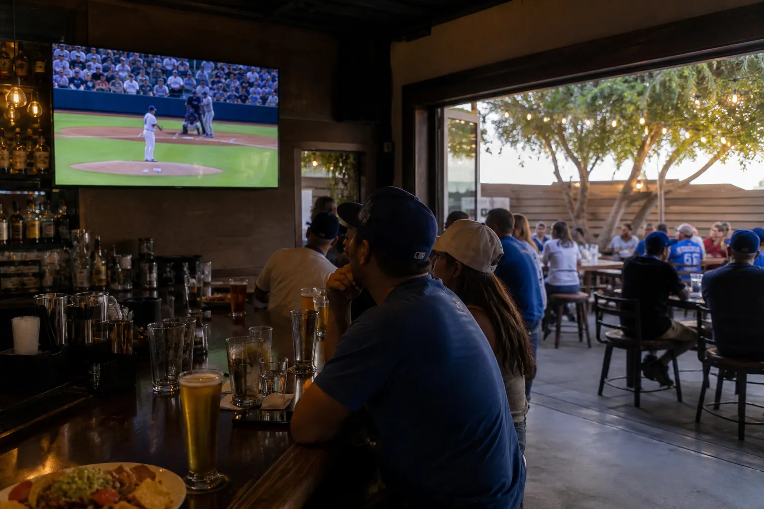 Inside a LA sports bar with a large screen visible over the counter and patio seating nearby