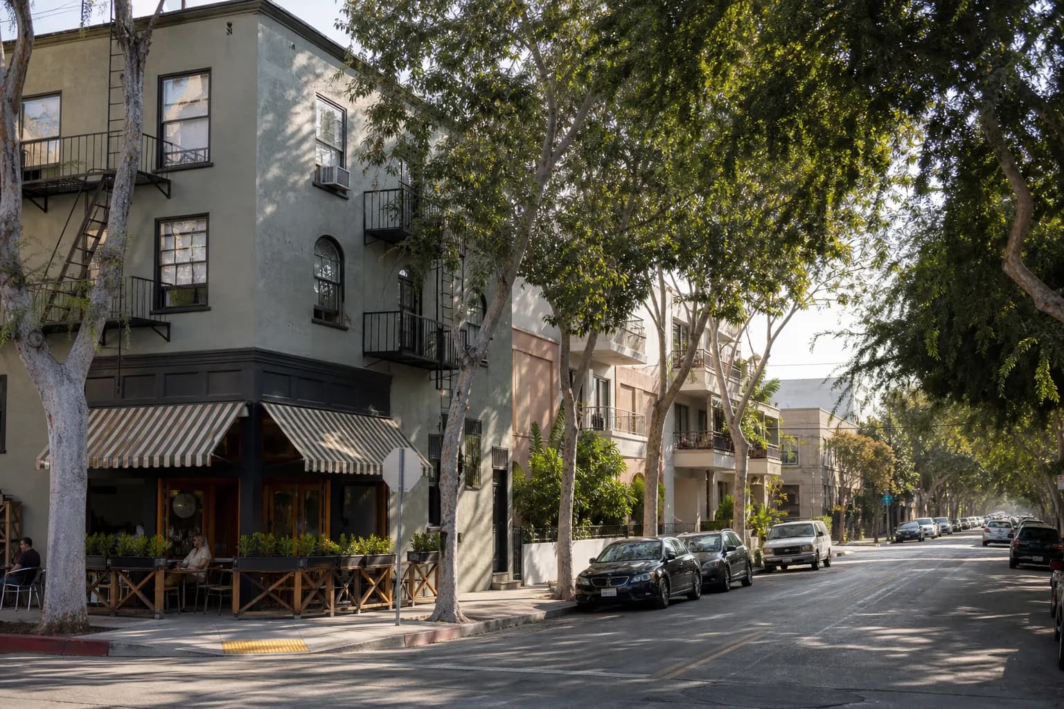Sunlit Los Angeles block with low-rise apartments and corner cafes