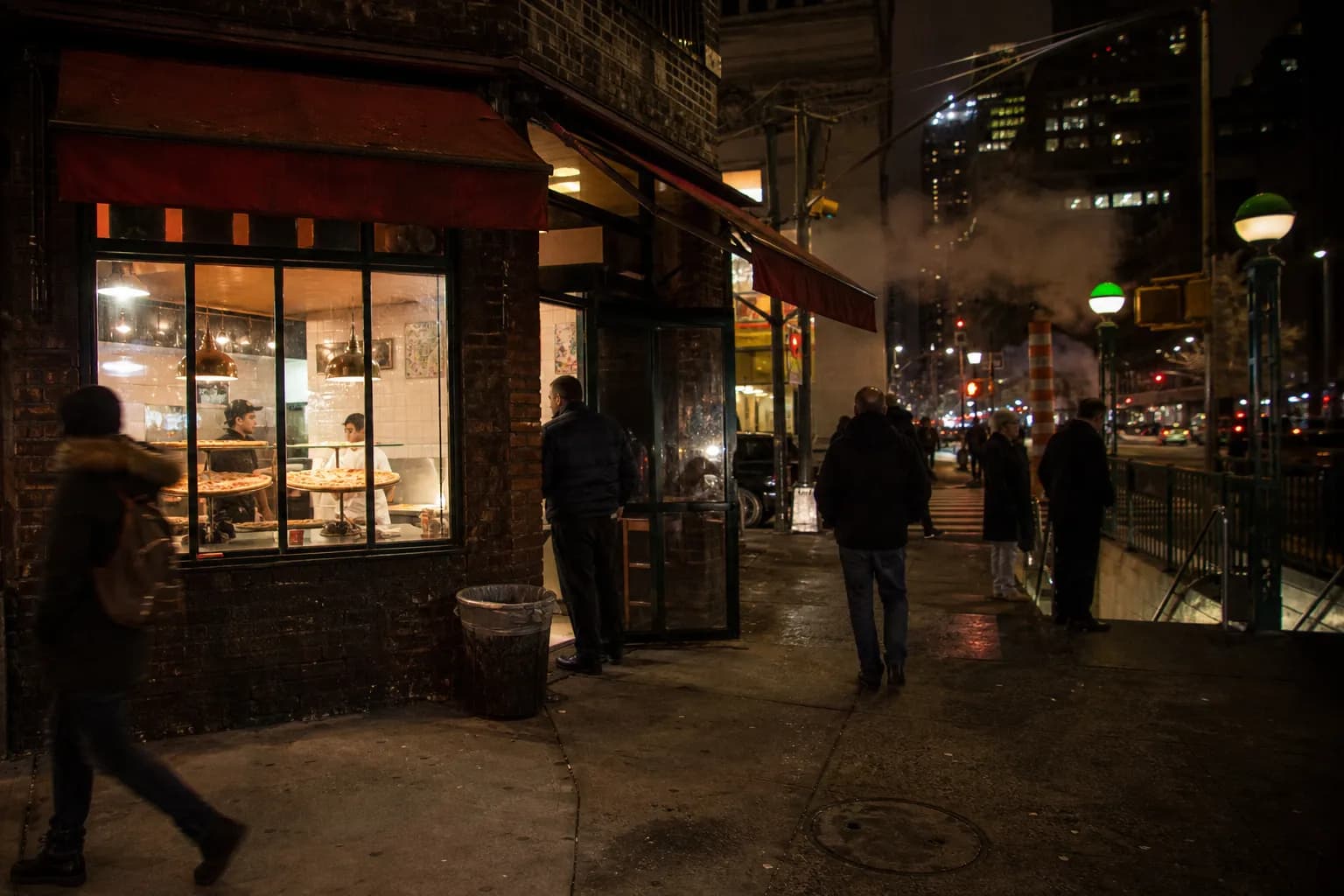 A glowing New York pizza counter on a busy late-night street