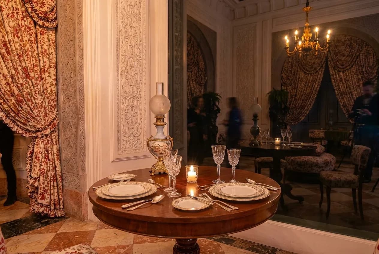 A window table set for two with the reflection of a room in the dark glass