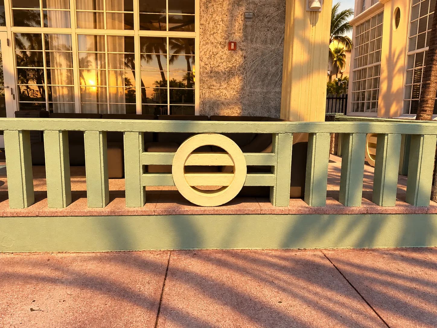 Pastel art deco facades with rounded corners and porthole windows at sunset, palms casting long shadows