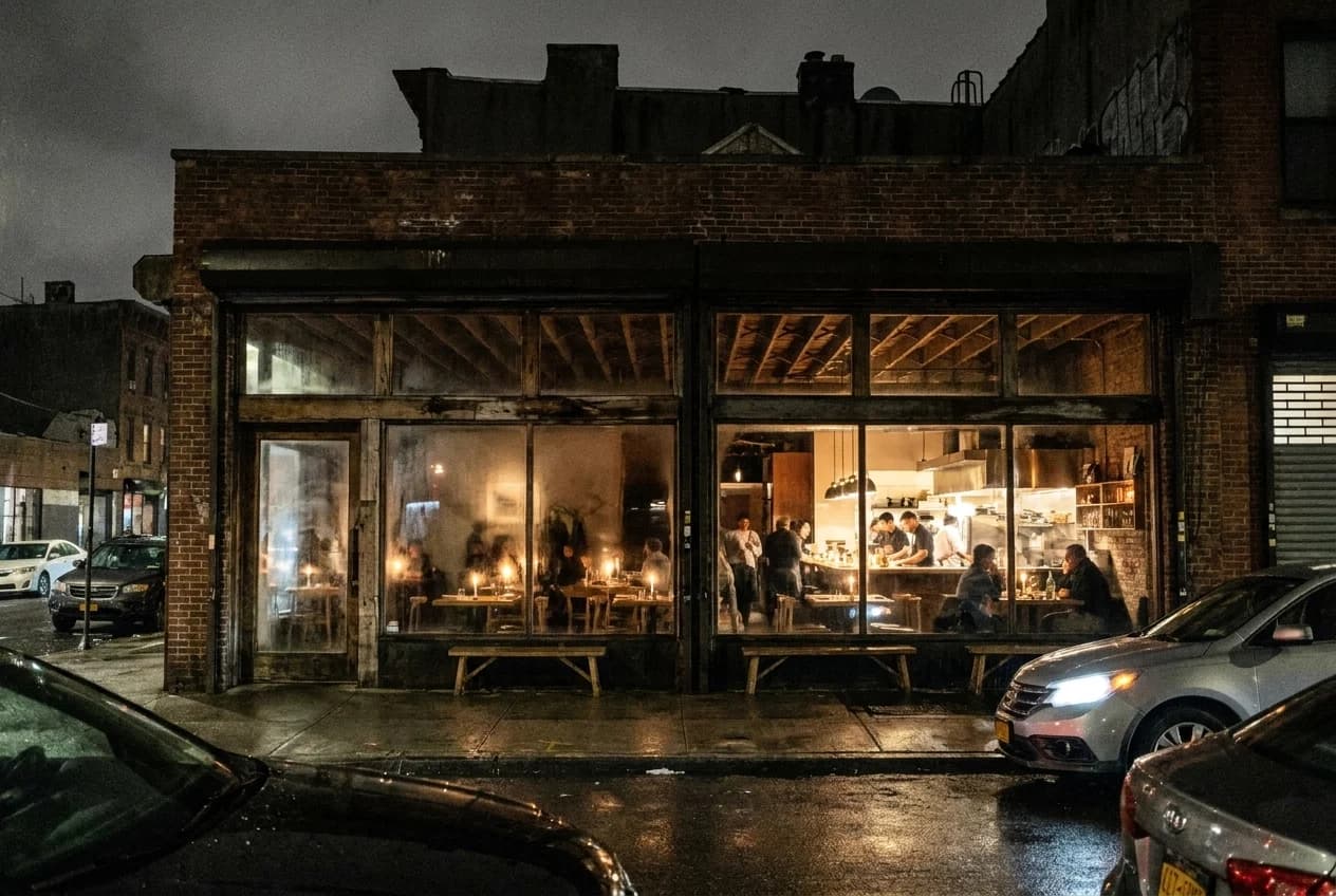 Open kitchen and candlelit tables in a Williamsburg Nordic tasting room with bare wood and low ceilings