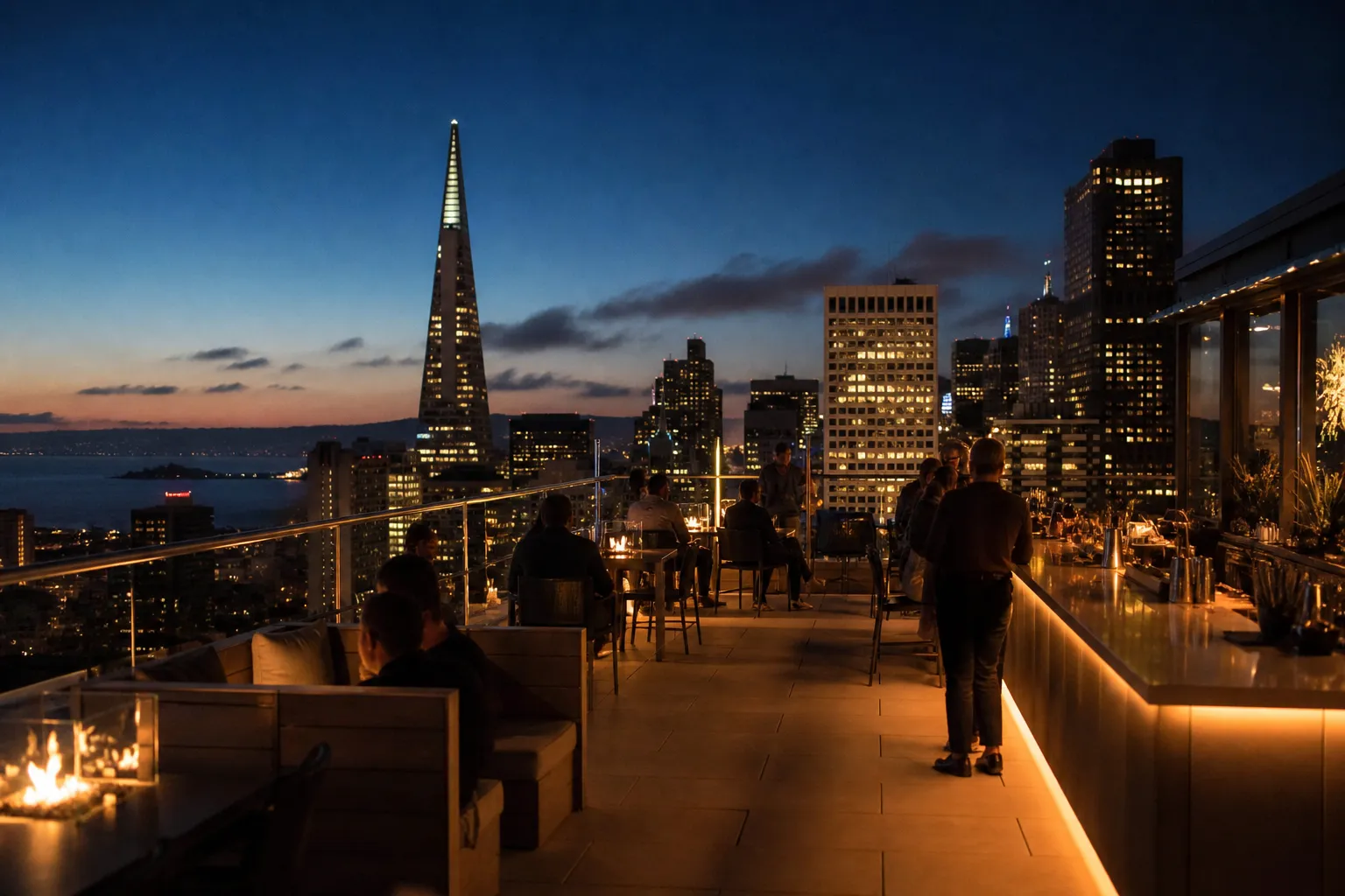 A rooftop bar glowing after sunset with the skyline behind it