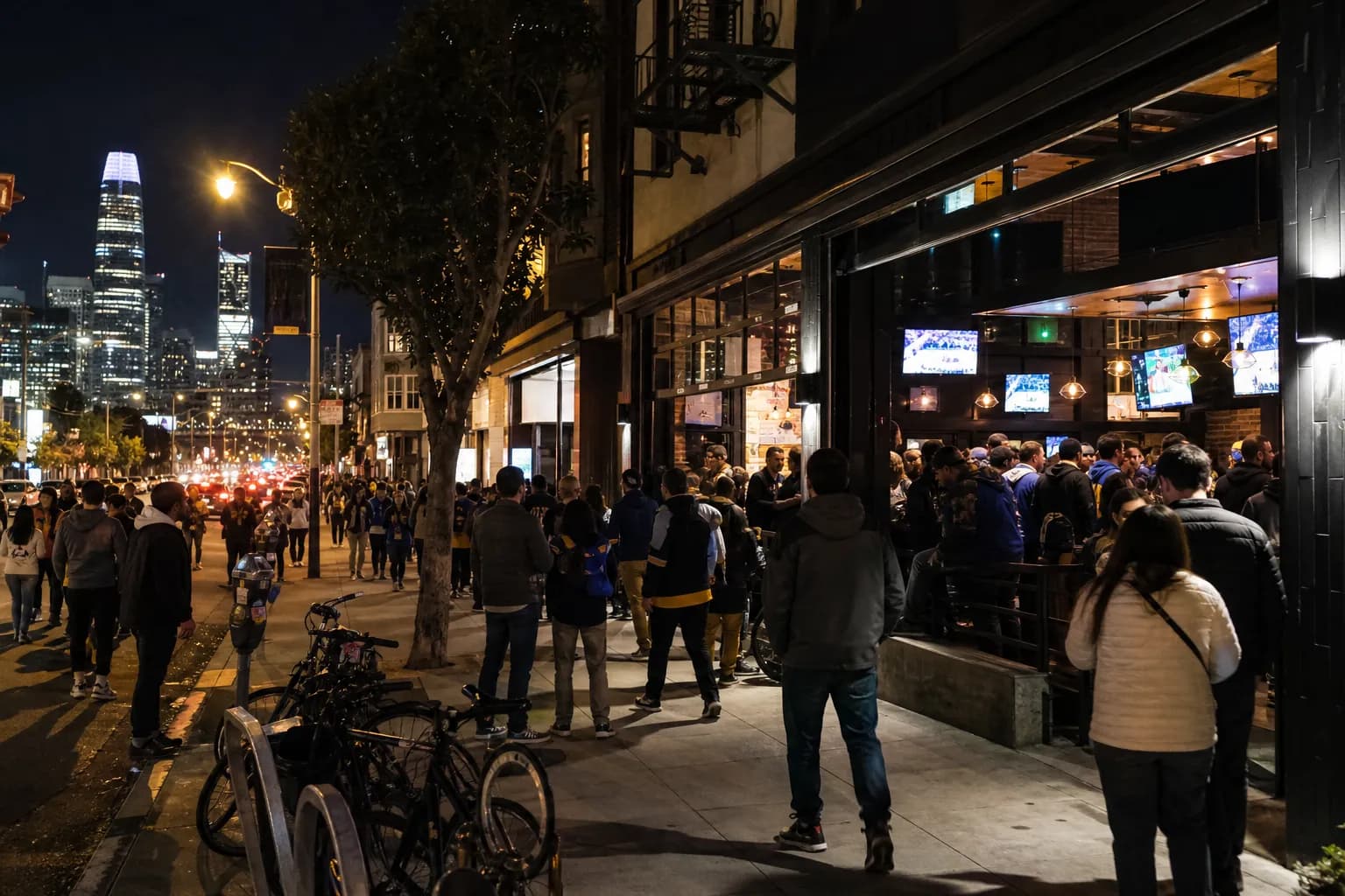 Night street view of a busy San Francisco neighborhood bar block with glowing windows before a game.