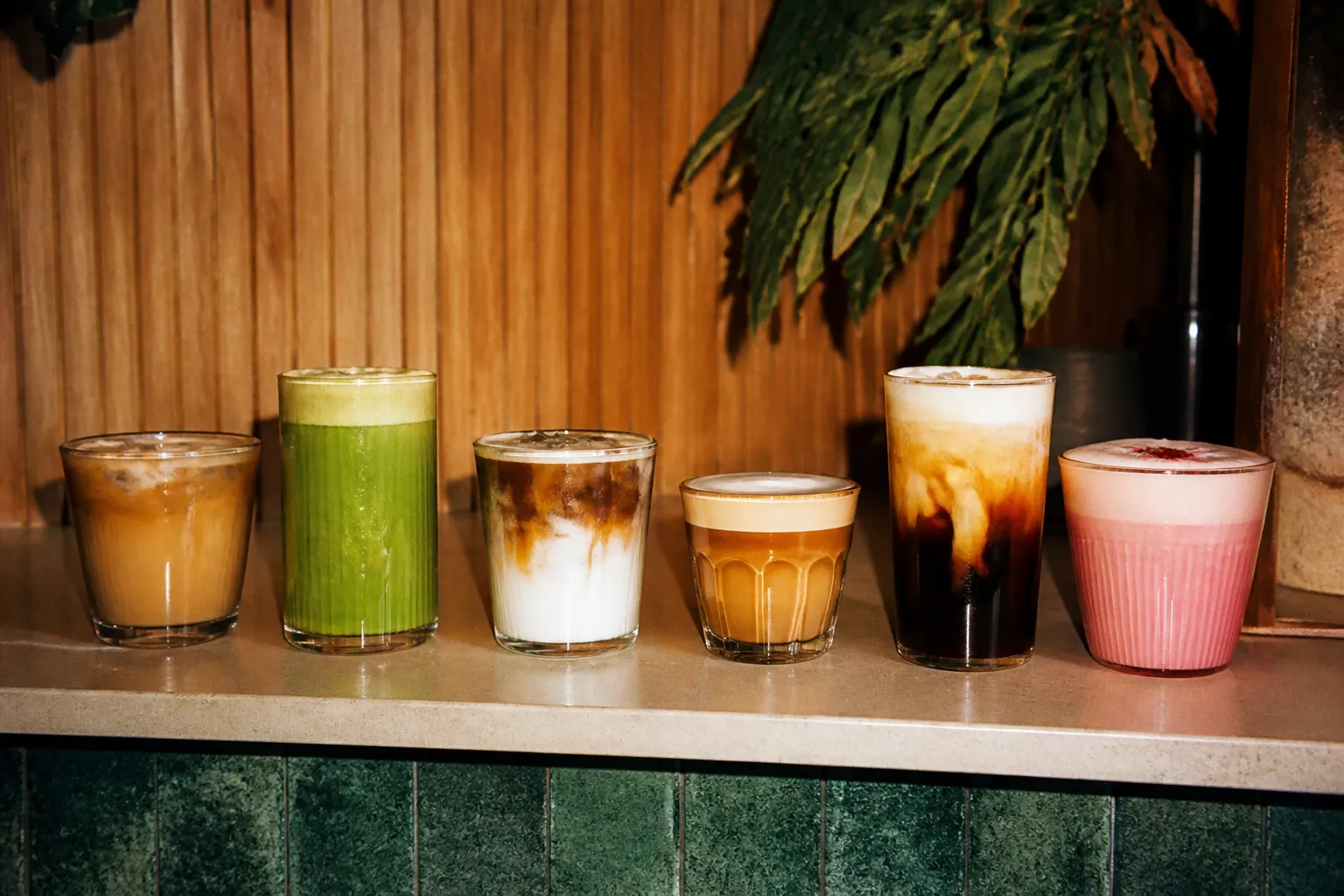 A lineup of colorful coffee drinks arranged on a cafe counter