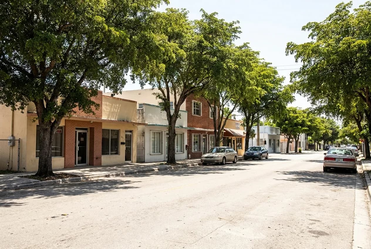 Bright afternoon sunlight on a quiet Little River street with low-rise storefronts, parked cars and sidewalk shade trees framing a casual Vietnamese restaurant.