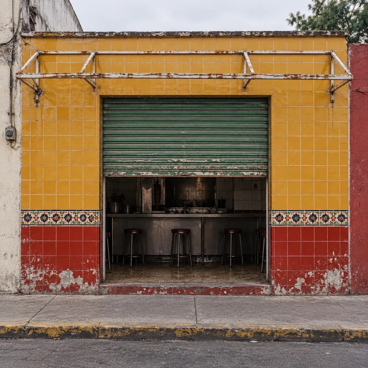 A tiled taqueria storefront in daylight with the shutter half down