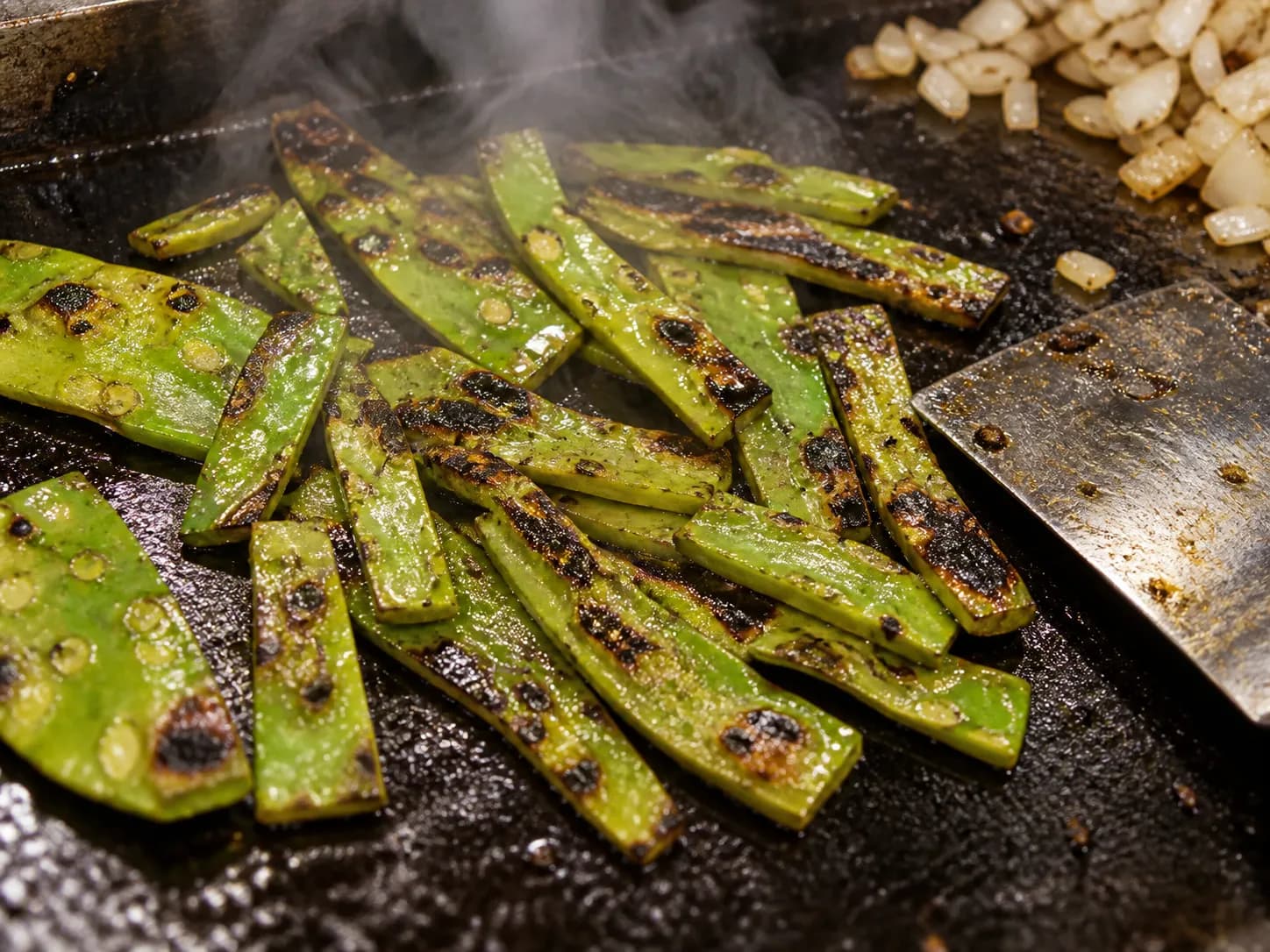 A grilled cactus paddle sliced on a hot flat-top griddle