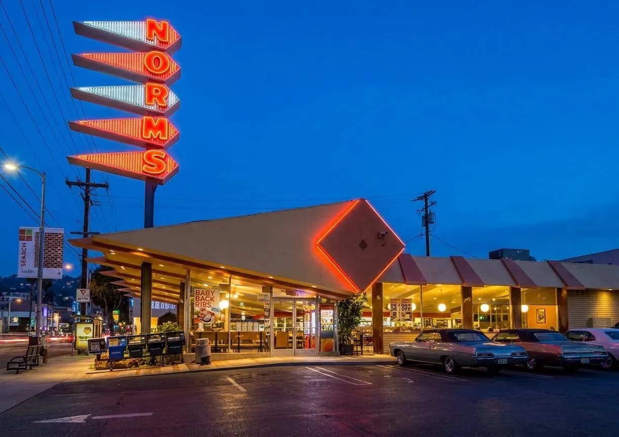 Neon-lit Los Angeles diner exterior at blue hour with chrome details and parked cars