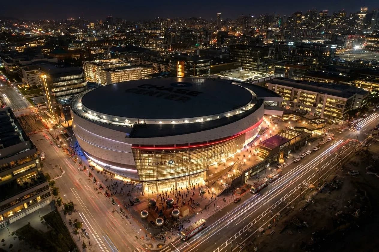 Chase Center glowing at night as concertgoers arrive in Mission Bay