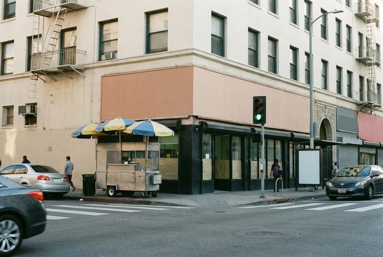 A dense Los Angeles neighbourhood street early in the morning with a food cart on the corner