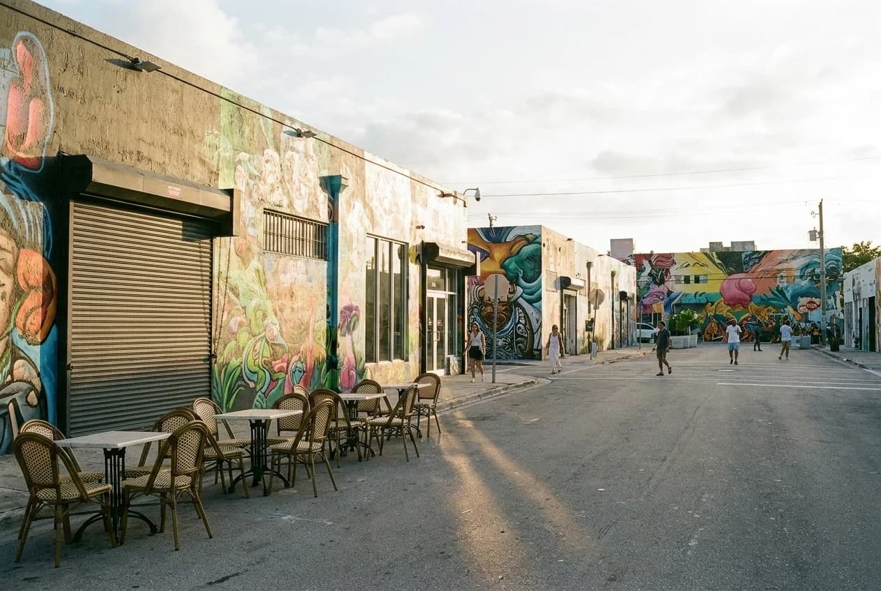 Empty sidewalk tables and painted warehouse murals on NW 2nd Avenue in Wynwood before the Saturday breakfast rush