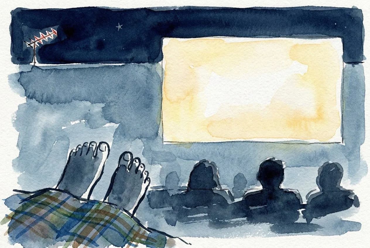AI-generated watercolor: a reclining viewer's perspective lying on a blanket at night, foreground silhouette of bare toes pointing up, mid-ground silhouetted heads of seated viewers, background a glowing blank white movie screen and the lit antenna of the Empire State Building visible in the upper left corner, deep navy night sky with one or two faint stars