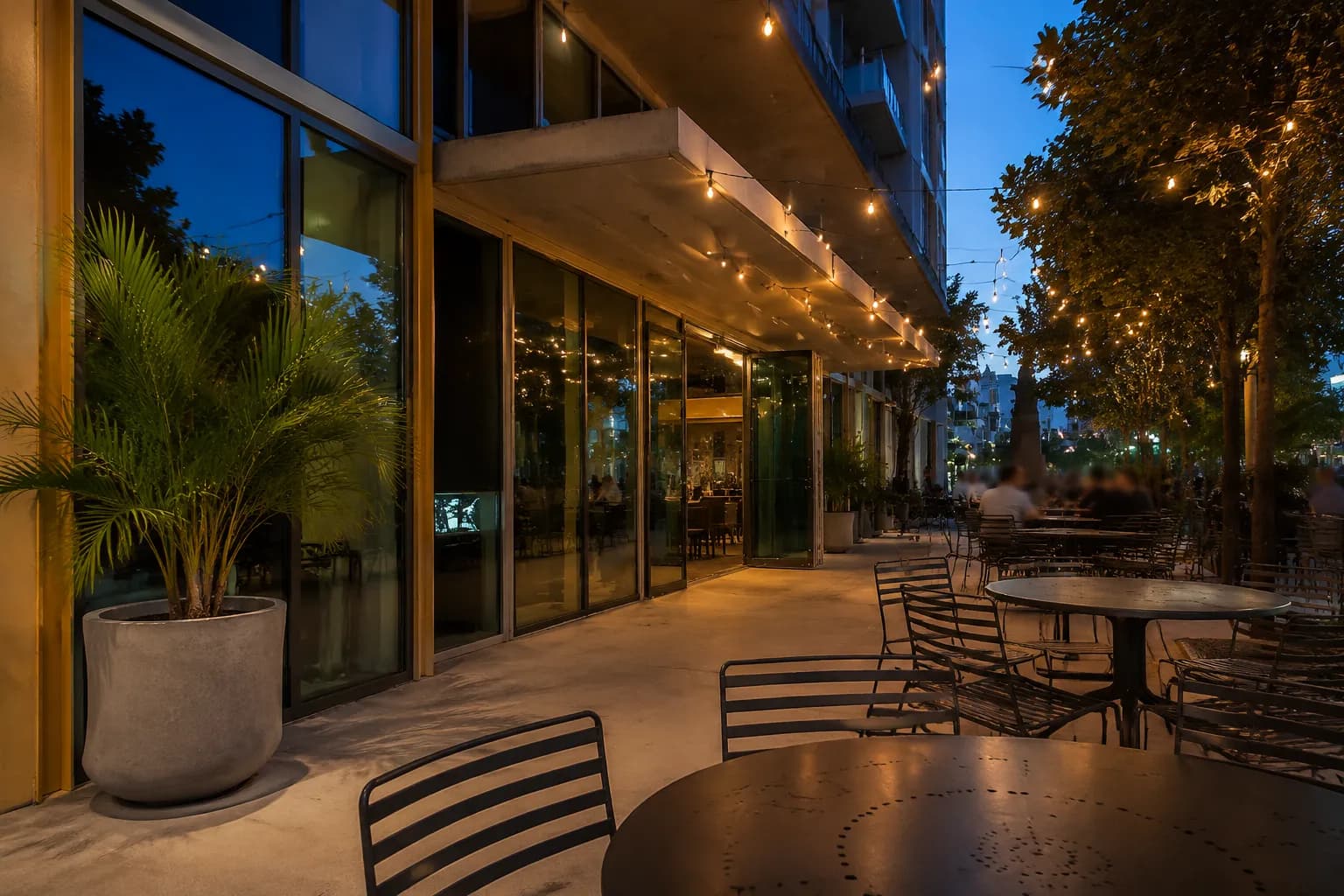Outdoor seating terrace at Mary Brickell Village with café tables, string lights, and storefronts at dusk