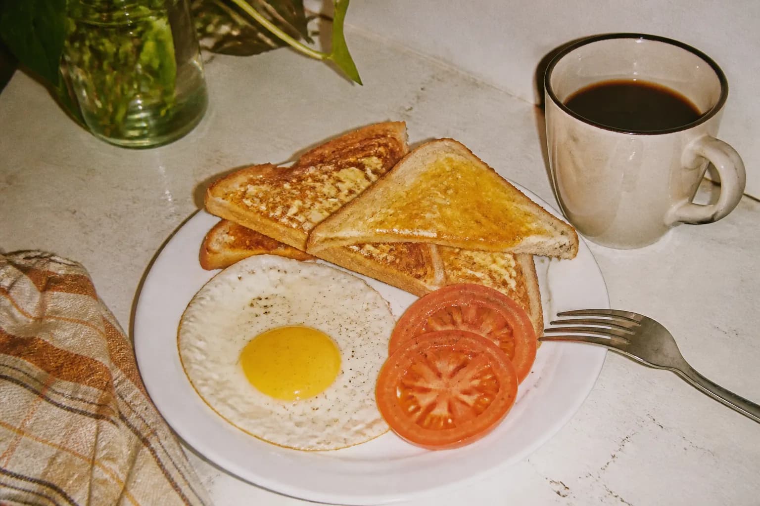 A simple budget-friendly breakfast plate with a cup of coffee on a plain table