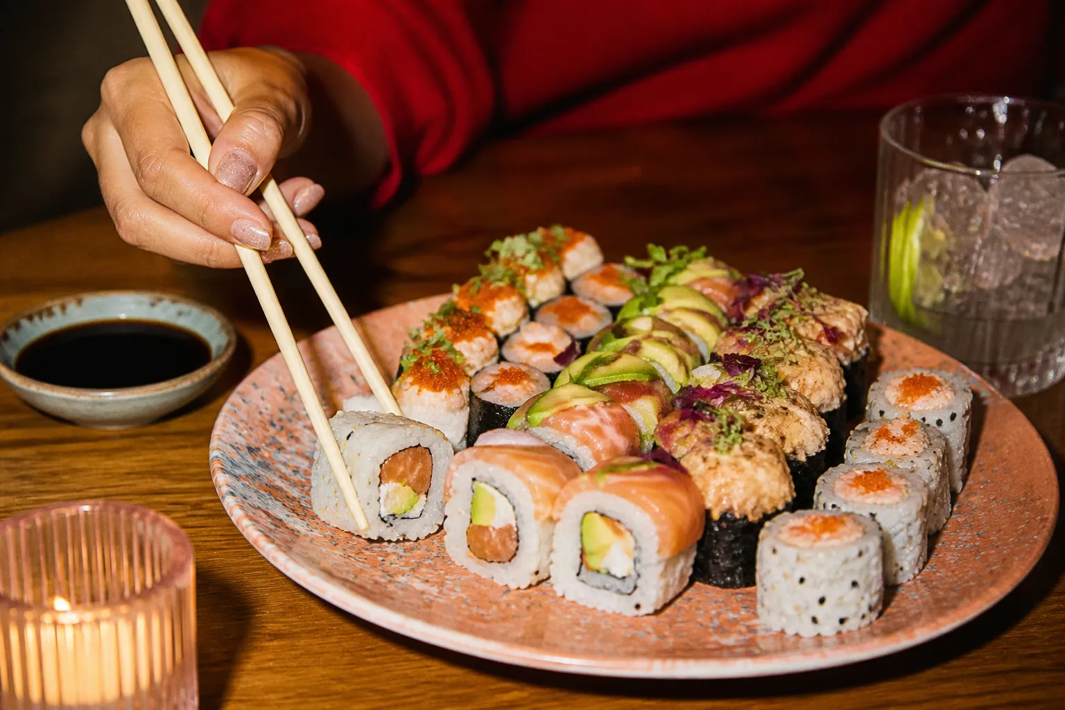 A colorful plate of assorted sushi rolls with chopsticks resting alongside