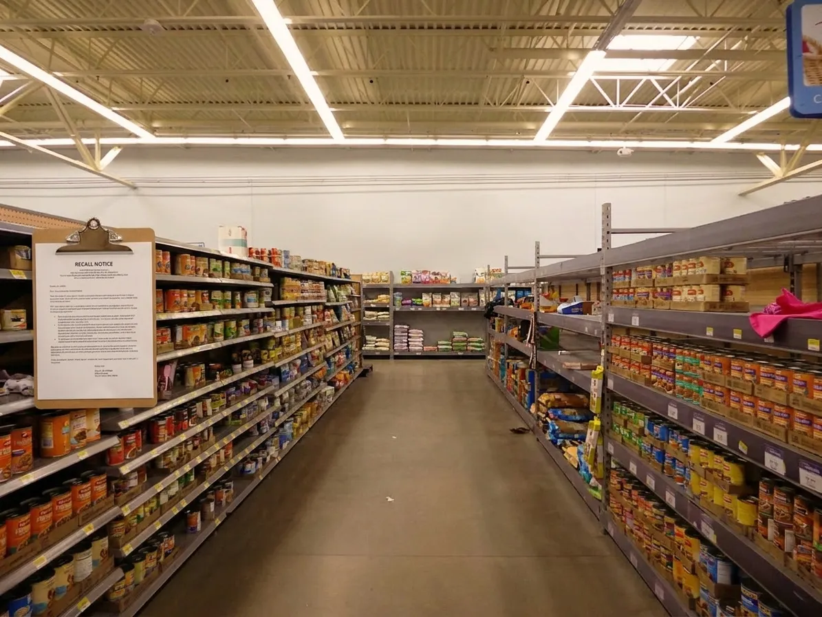 Interior view of pet food store shelves with canned dog food and recall notices