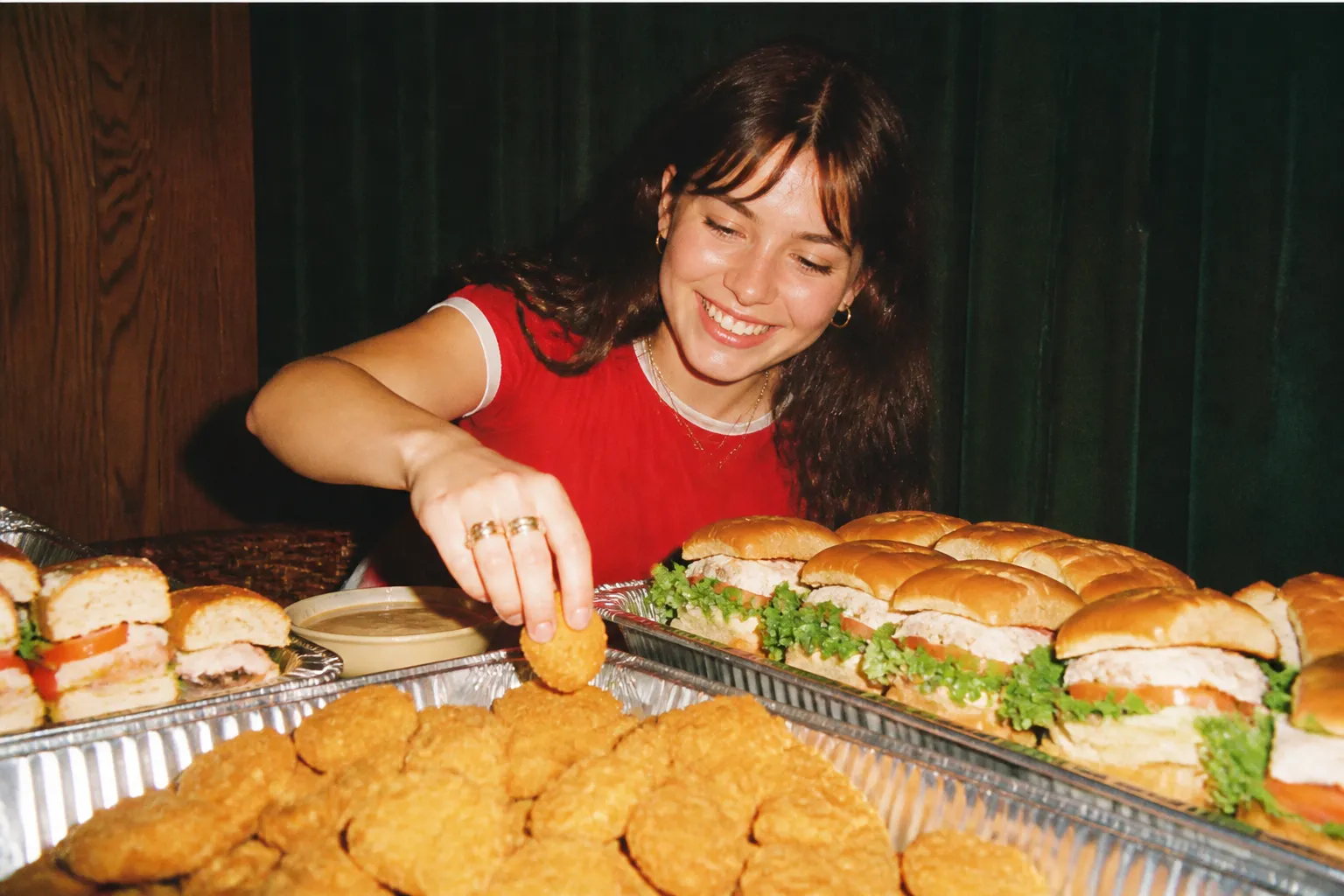 Large catering trays filled with golden nuggets and stacked chicken sandwiches for a group