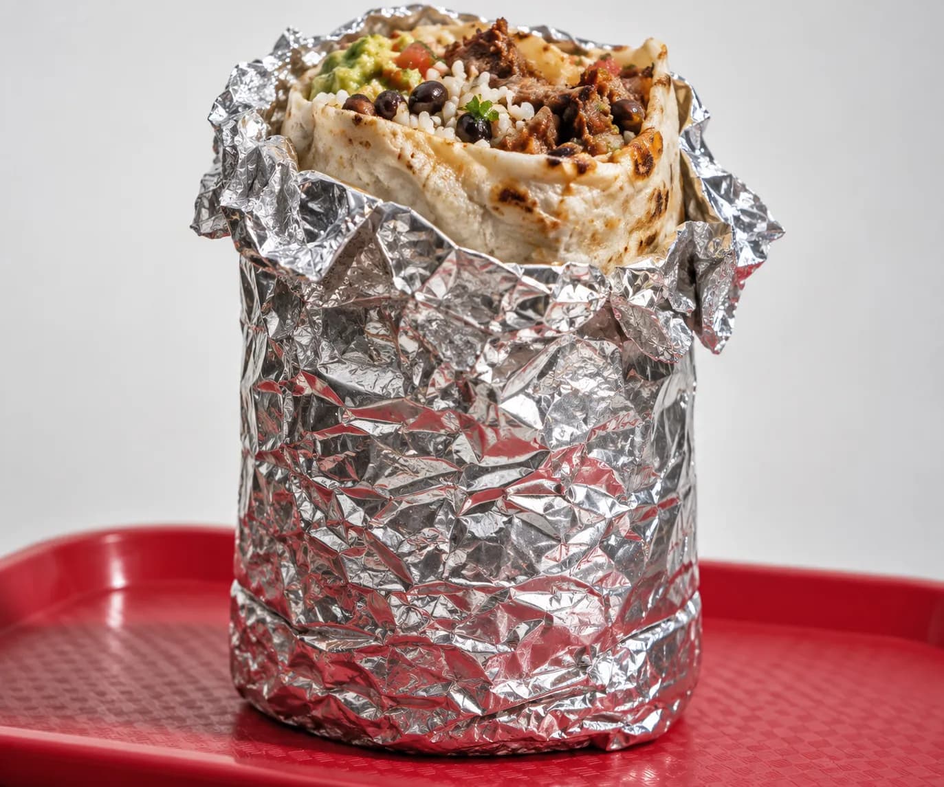 A heavy foil-wrapped burrito held upright on a tray