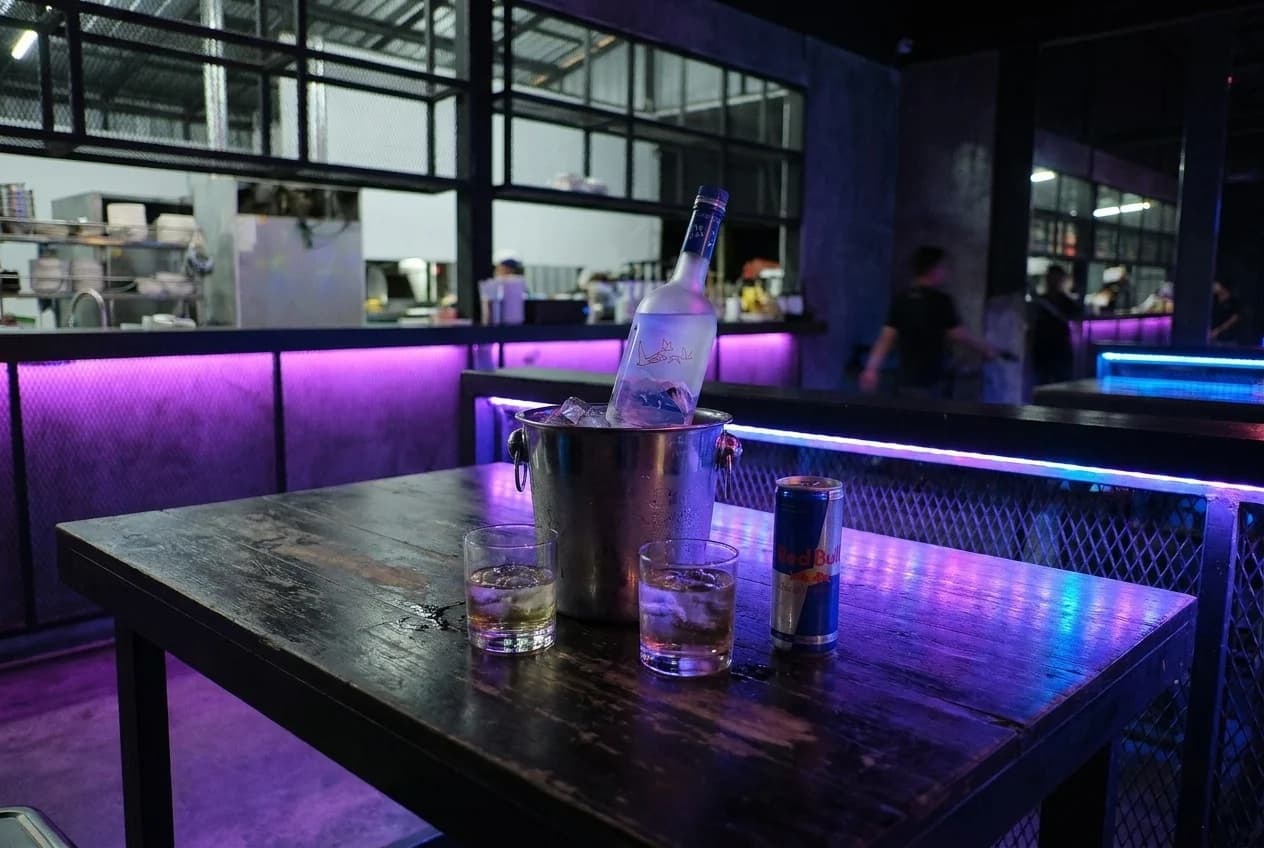 Vodka bottle in ice bucket with glasses and mixers on a nightclub table in Brickell, Miami