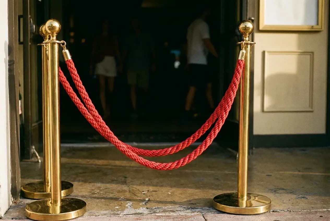 A looped rope slung between two weighted posts at an entrance, the floor beyond falling away into darkness