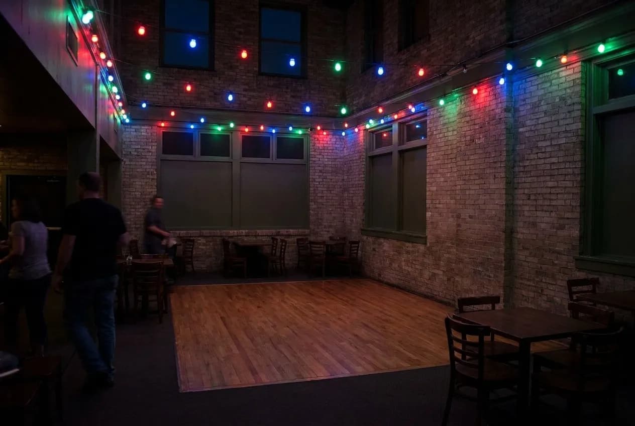 A dark back room with a small dance floor and coloured lights on the ceiling