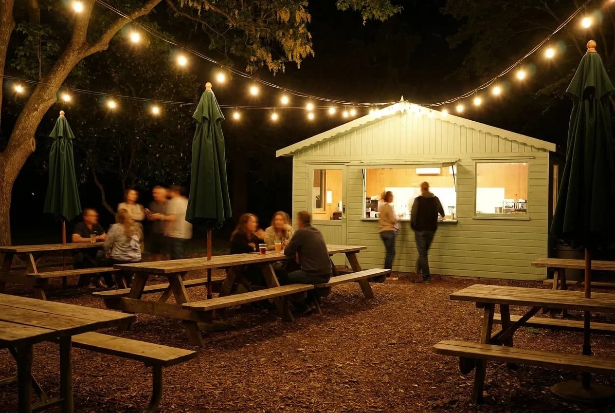 A string-lit outdoor bar patio with picnic benches at night