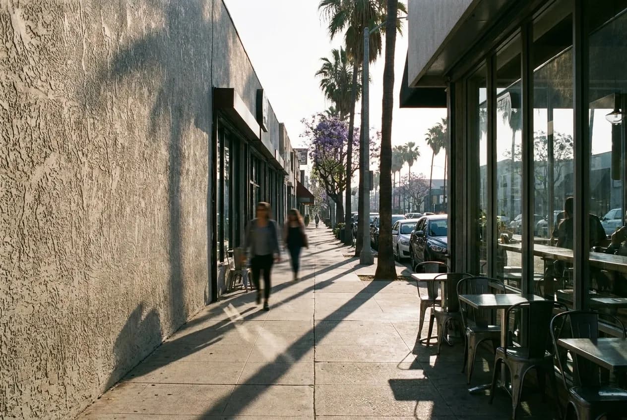 Morning light on a commercial boulevard in Highland Park with cafe storefronts and sidewalk seating