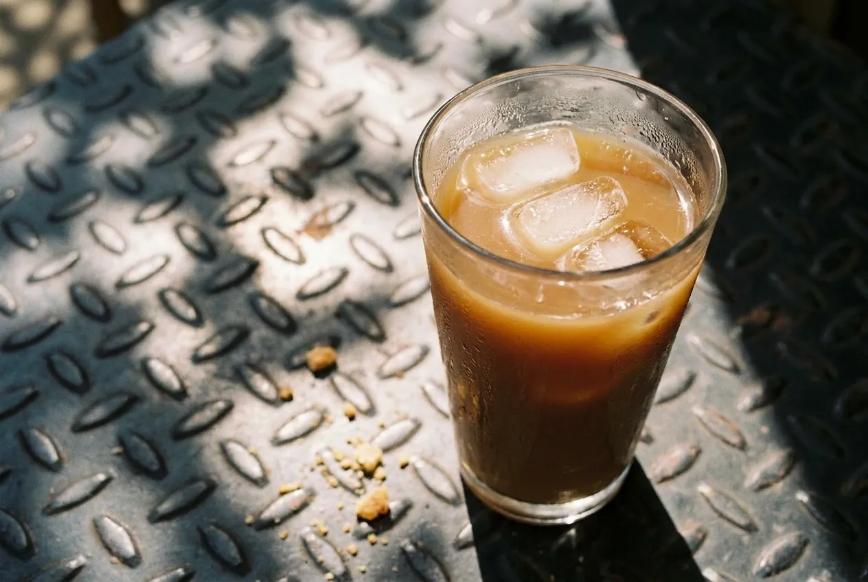 Iced coffee on an outdoor cafe table in dappled morning sunlight
