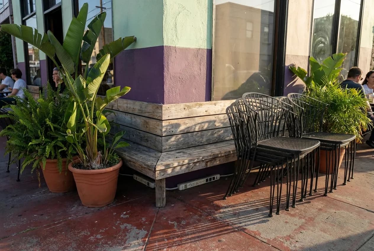 A cafe corner with a power outlet strip along a bench seat and stacked chairs